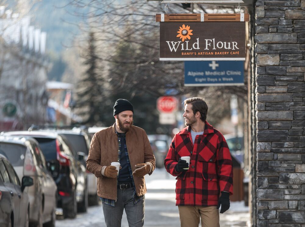 Two people walking down Bear Street with coffees in hand